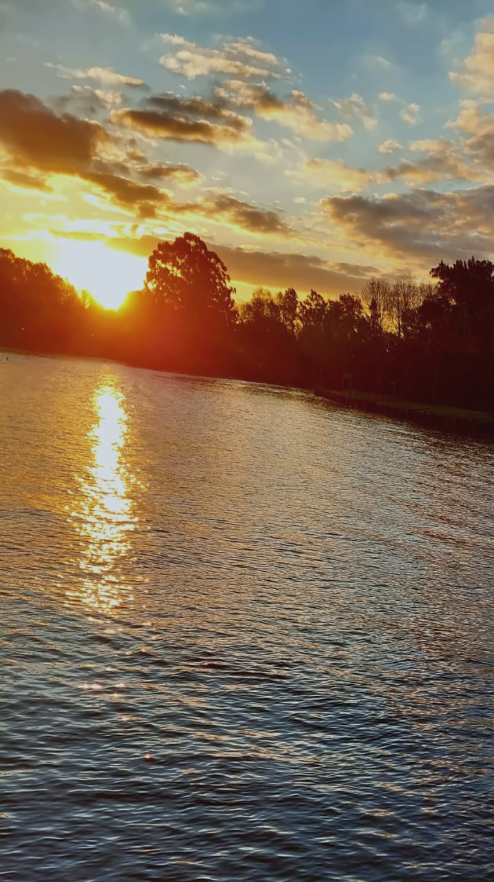 Sol bajando sobre el río Sarmiento y reflejándose en el agua.